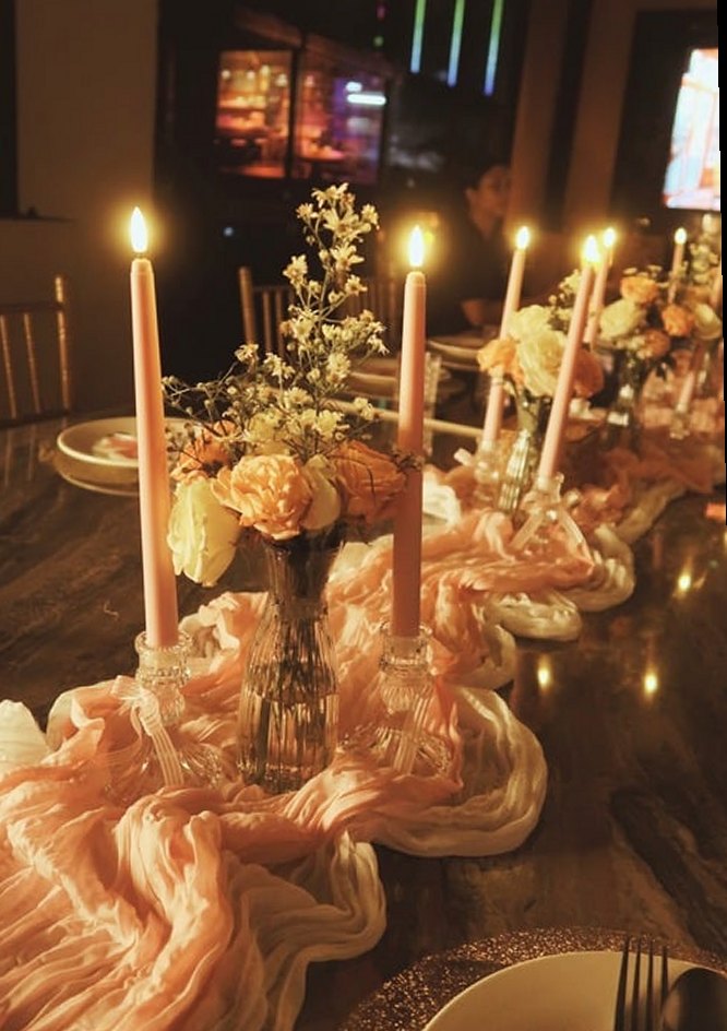 A candlelit table dressed with a blush runner, taper candles and flowers